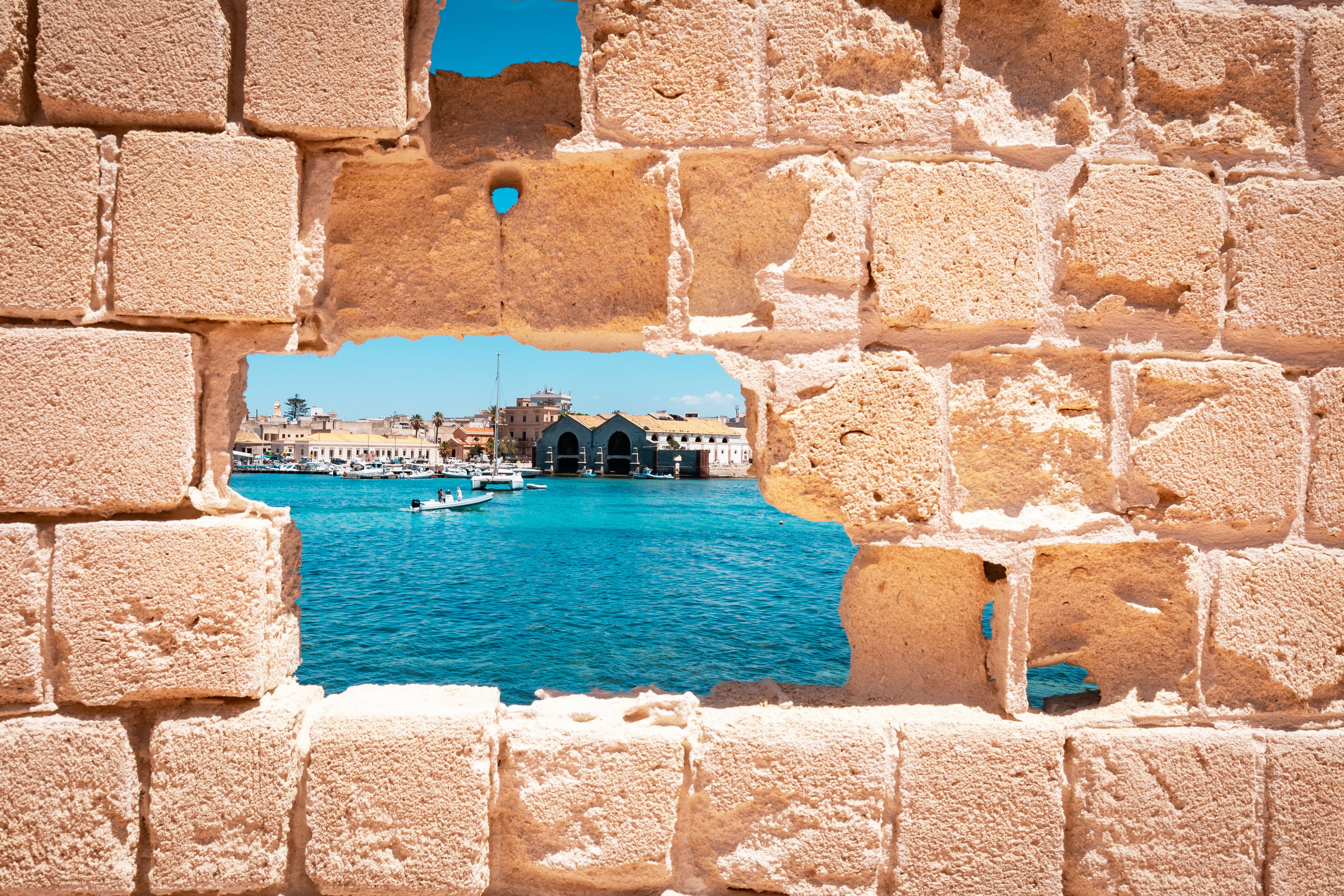 The Sicilian sea behind a brick wall